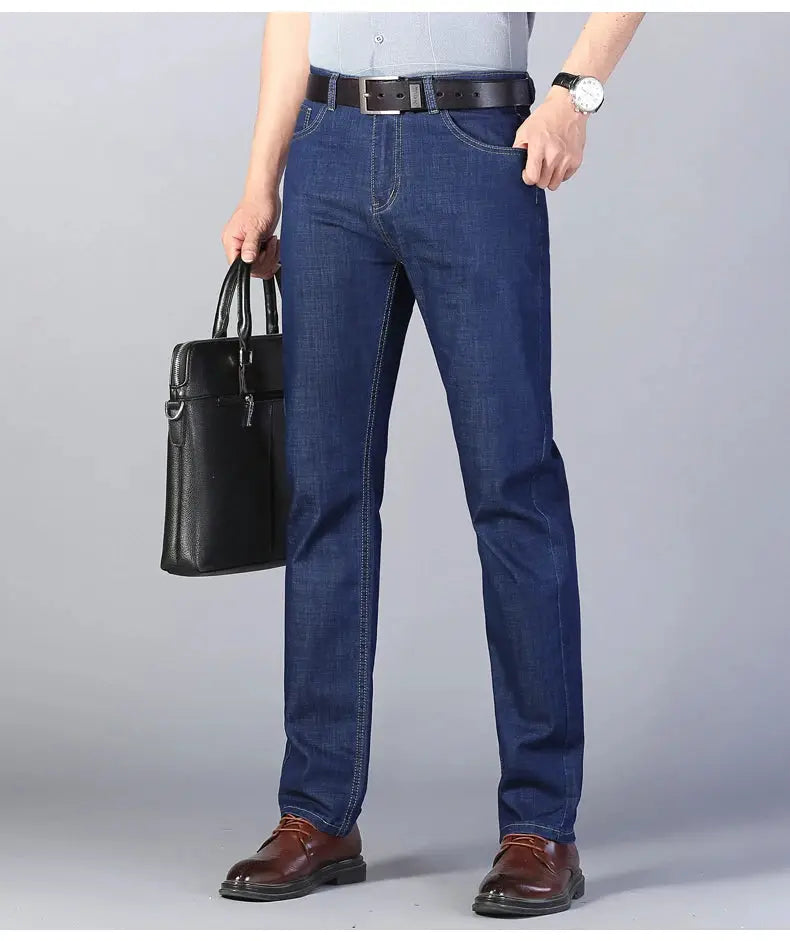 Men's blue denim jeans with contrast stitching and straight leg fit, shown with brown belt and brown dress shoes.