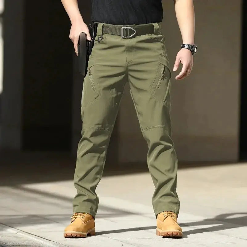 Men's tactical cargo pants, olive green softshell with multiple zip pockets and belt-compatible waist.