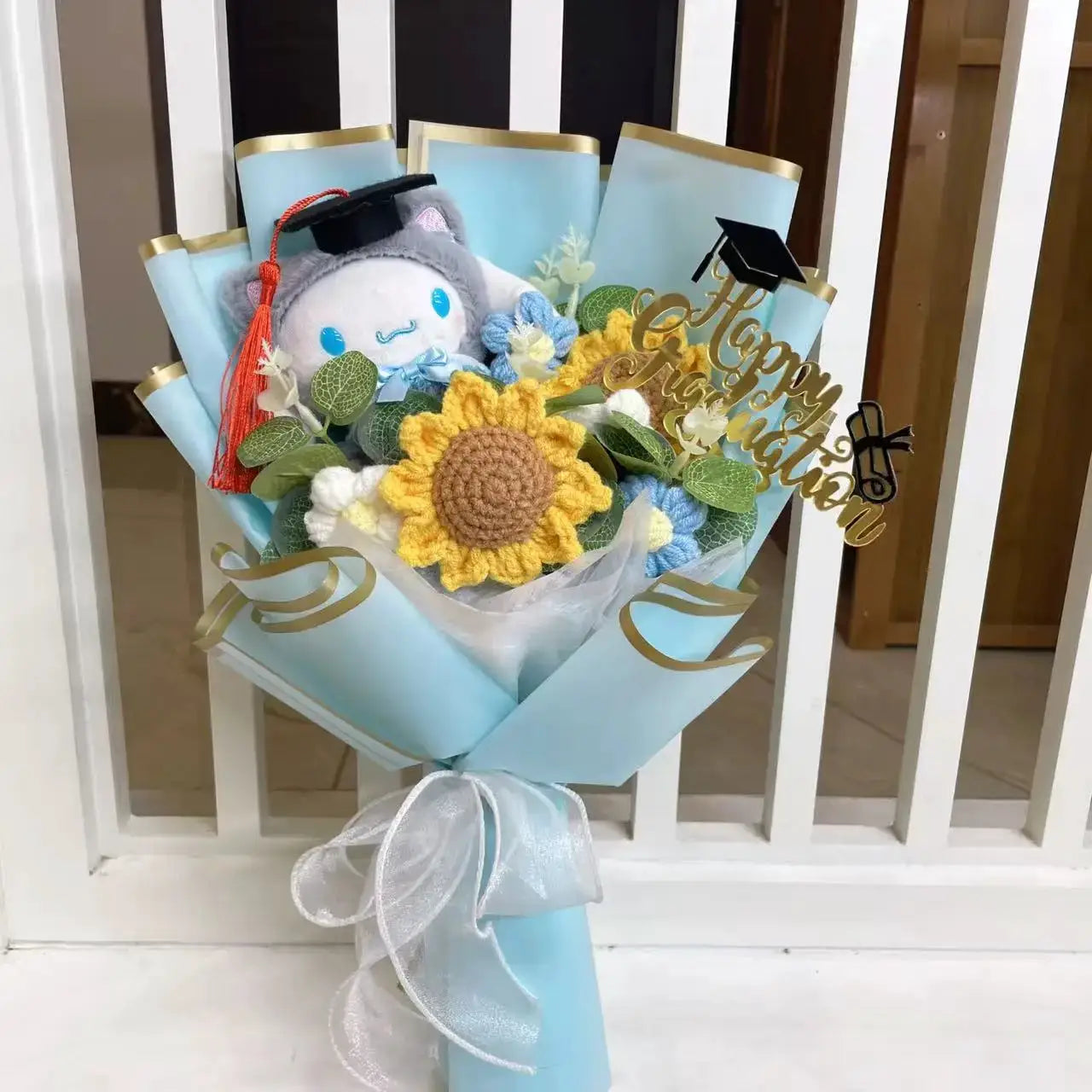 Stuffed plant bouquet in light blue wrap with crocheted sunflowers and plush mascot wearing a graduation cap