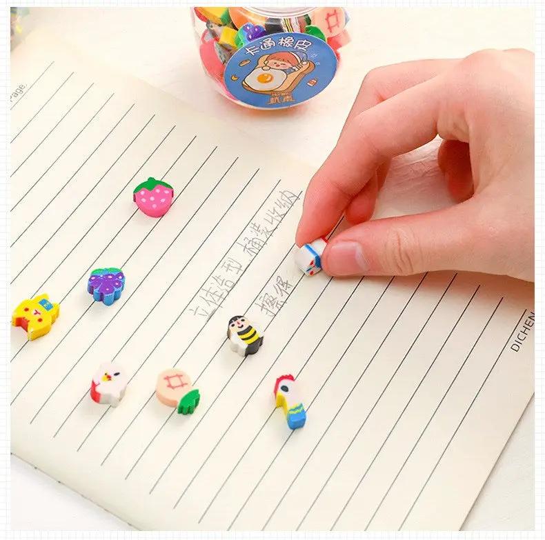 Simples Market kawaii erasers set; colorful animal and fruit rubber pencil erasers, 9 pieces shown on lined notebook
