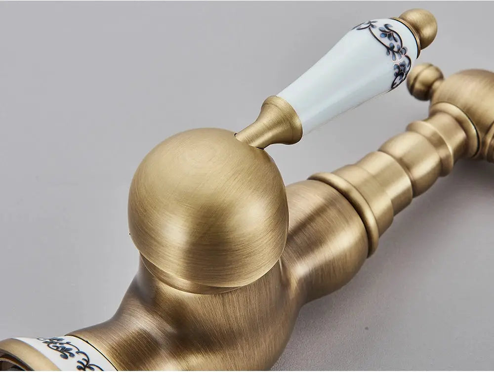 Antique brass bathroom faucet with rotating spout and blue-floral ceramic detail