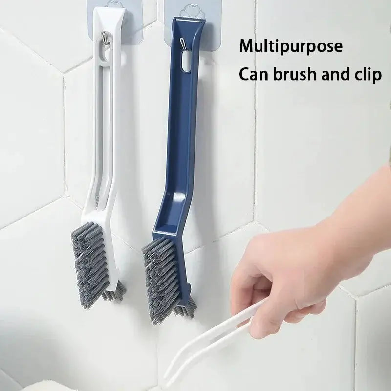 Two 2-in-1 cleaning brushes with white and blue handles, hanging on tiled wall for corners and gaps
