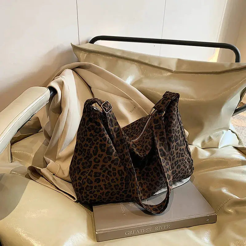 Leopard print shoulder bag with large capacity, soft textile finish on a beige chair