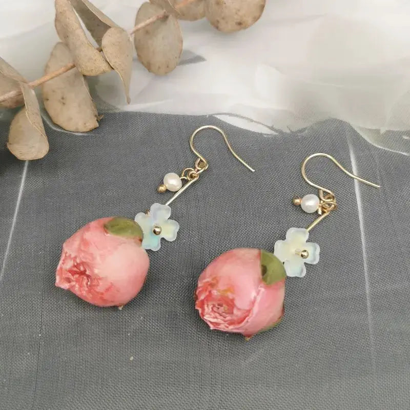 Red rose epoxy resin drop earrings pair by Simples Market with pale blue flower accents