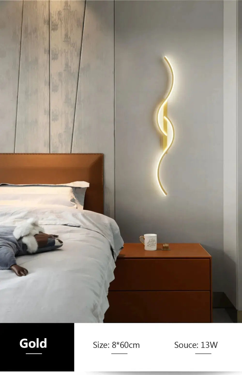 Gold LED wall lamp, minimalist long curved strip, mounted beside bed on gray wall.