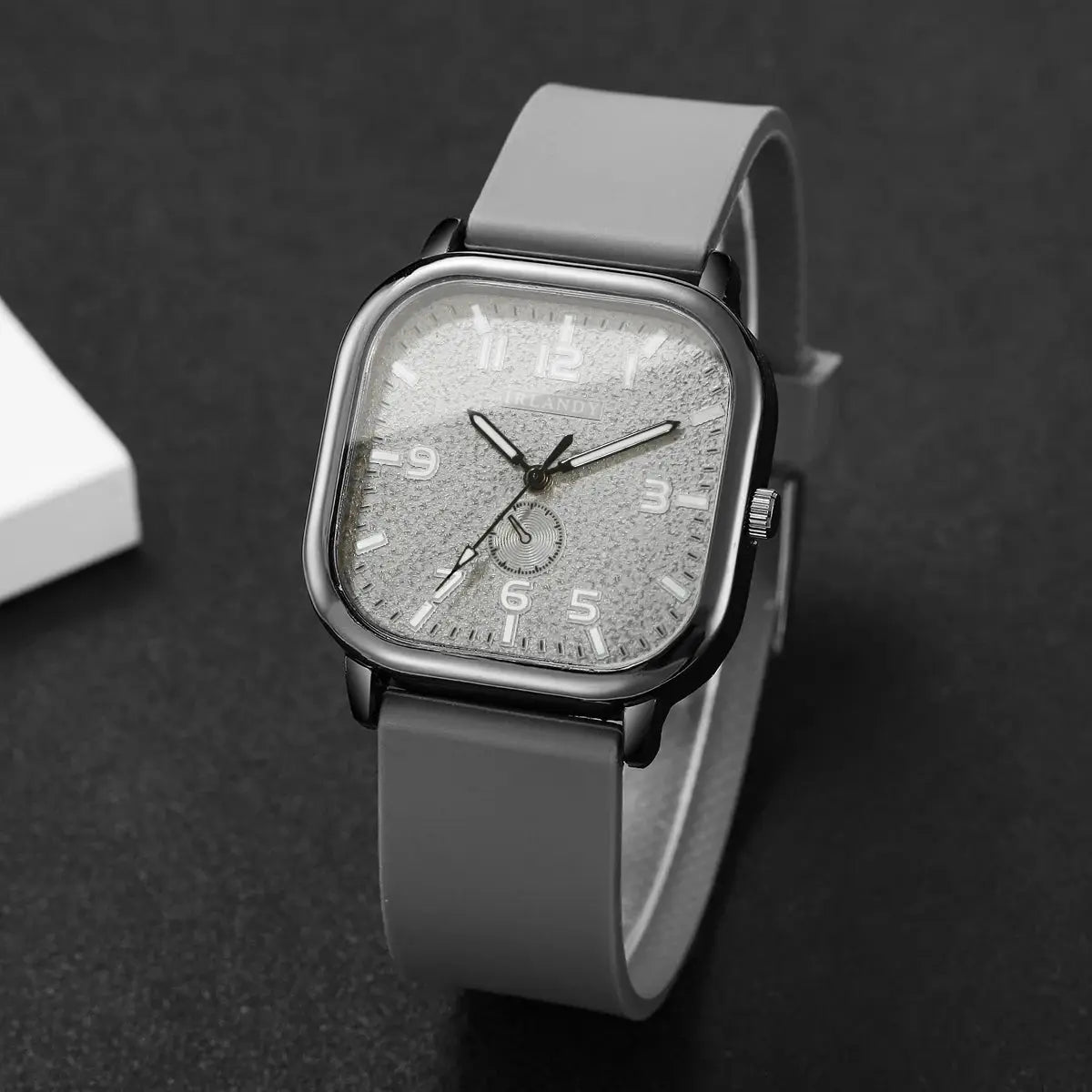 Square watch with gray silicone strap and textured silver dial, quartz movement.
