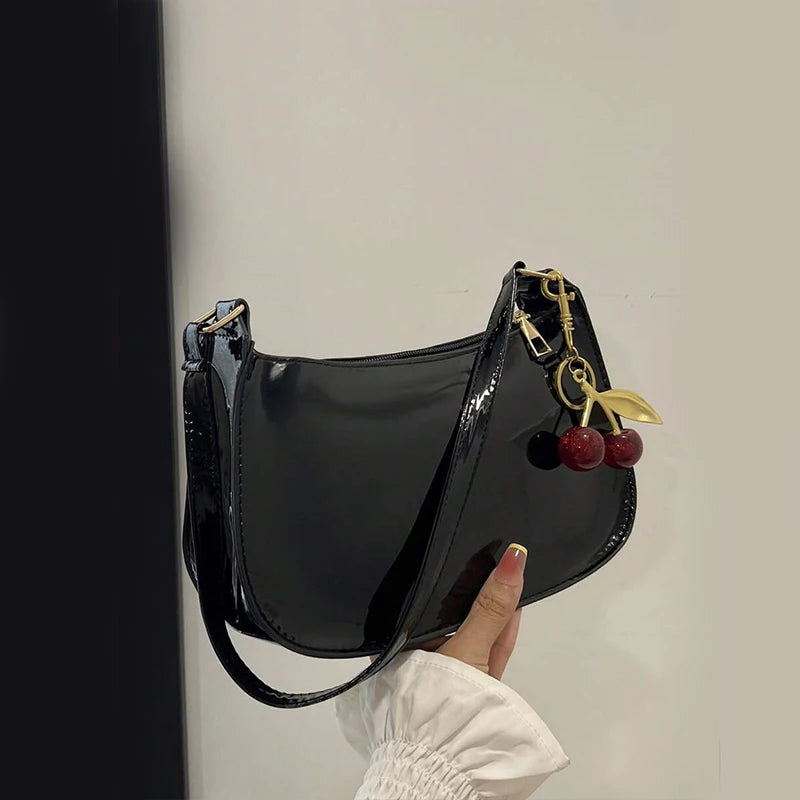 Women's black PU leather shoulder bag with cherry pendant charm and gold hardware by Simples Market