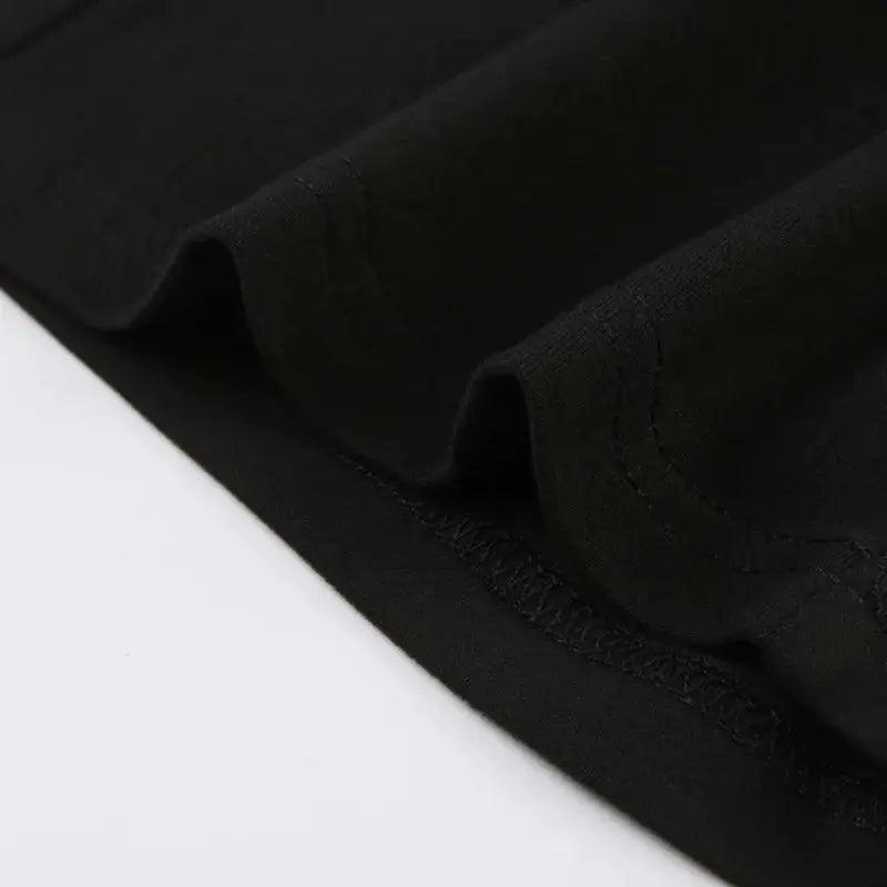 Women's black jumpsuit fabric close-up with folded hem and neat stitching