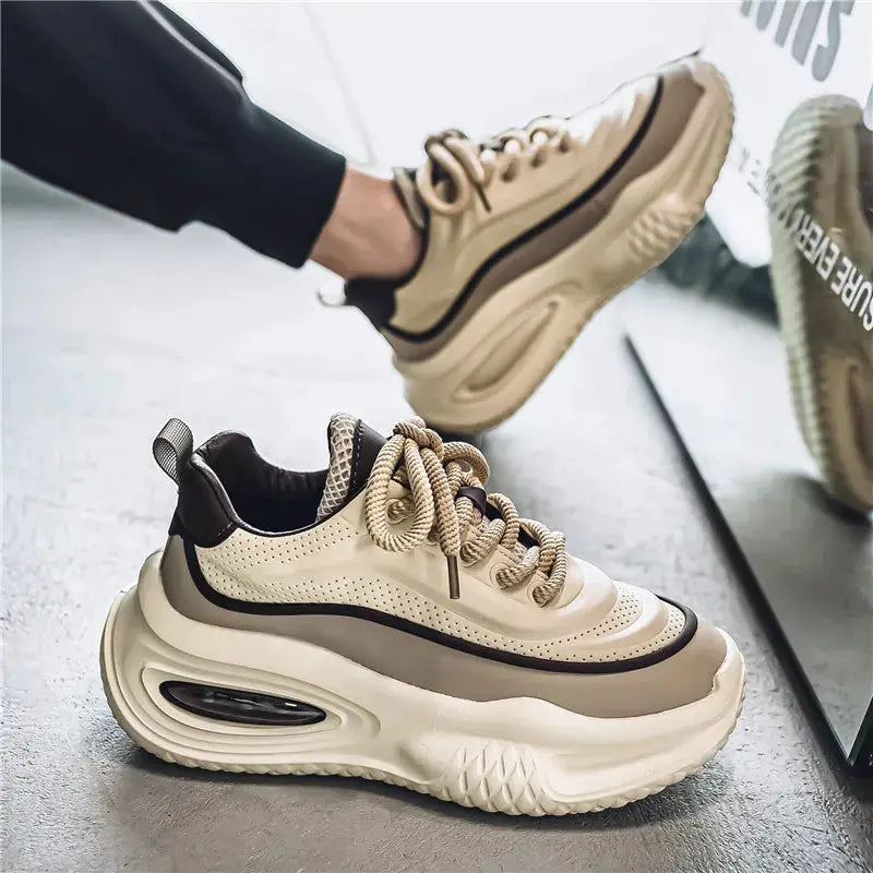 Pair of men's thick-soled beige sneakers with black trim and braided laces, casual outdoor skate shoes.