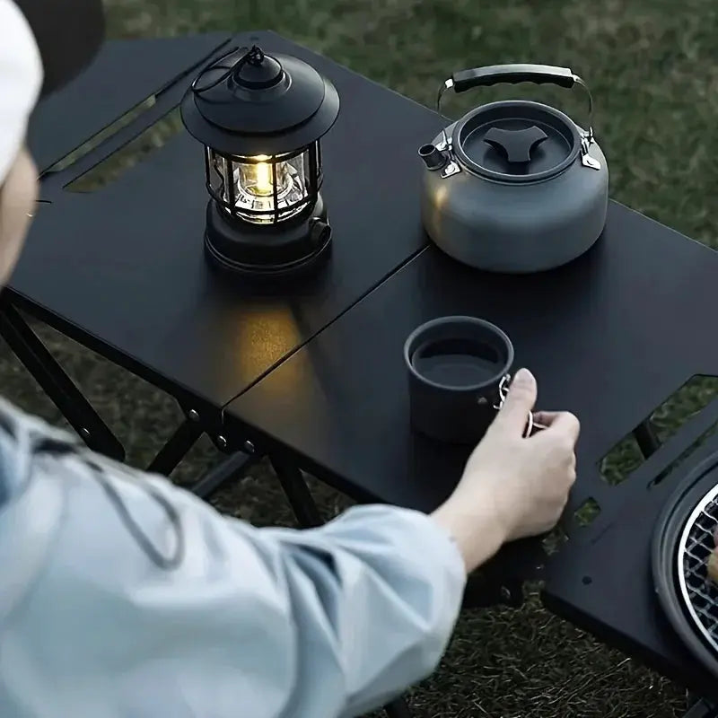 Portable folding camping table by Simples Market, black stainless steel outdoor dining table with lantern and kettle