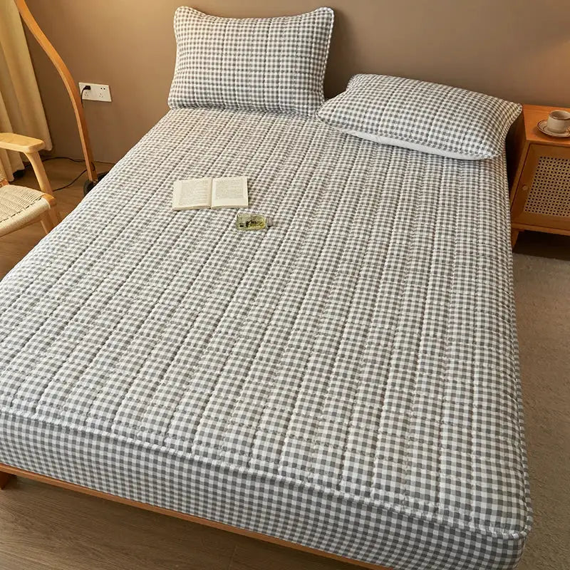 Quilted plaid mattress cover in gray and white; breathable antibacterial protector