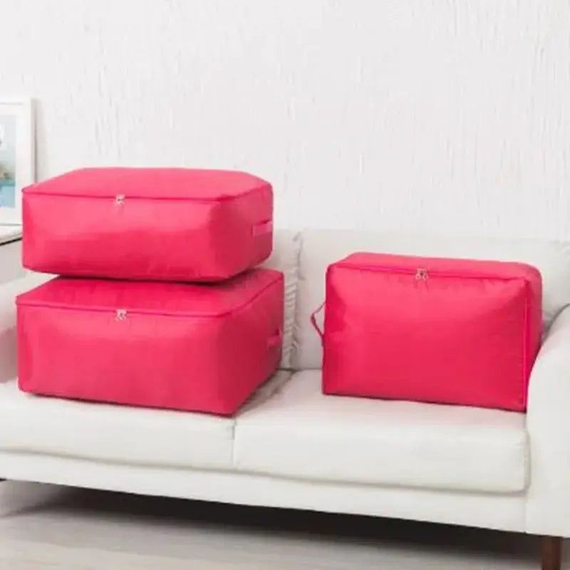 Three pink zipper clothes organizer bags on a white sofa; large bedding storage.