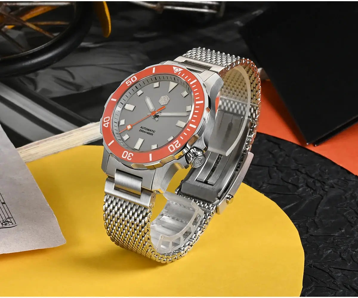 San Martin diver watch with red bezel, grey dial, luminous markers, and stainless steel Milanese bracelet