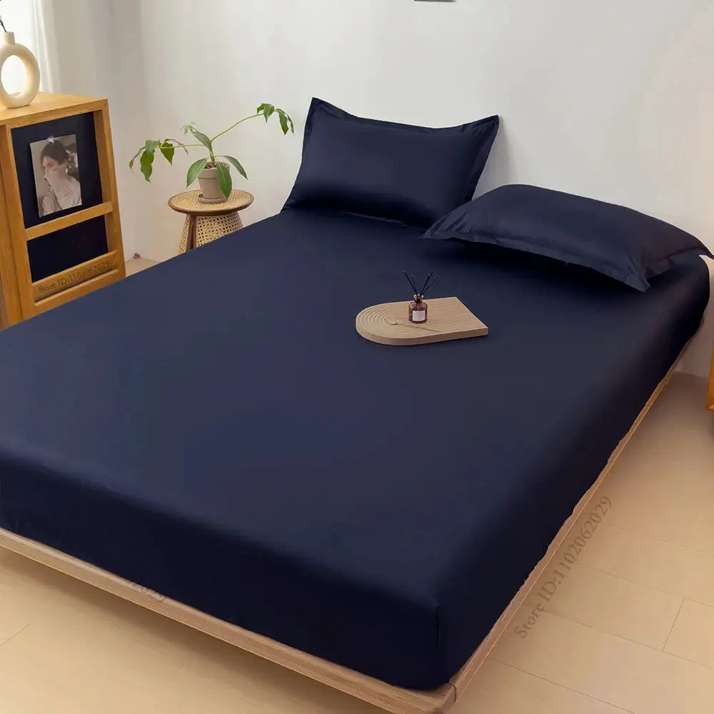 Waterproof mattress protector fitted sheet by Simples Market in navy blue on bed with two matching pillows