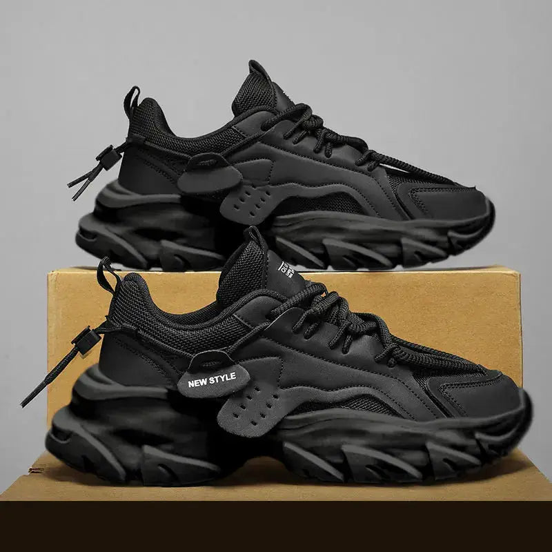Two black thick-soled men's sneakers with breathable mesh on a cardboard box