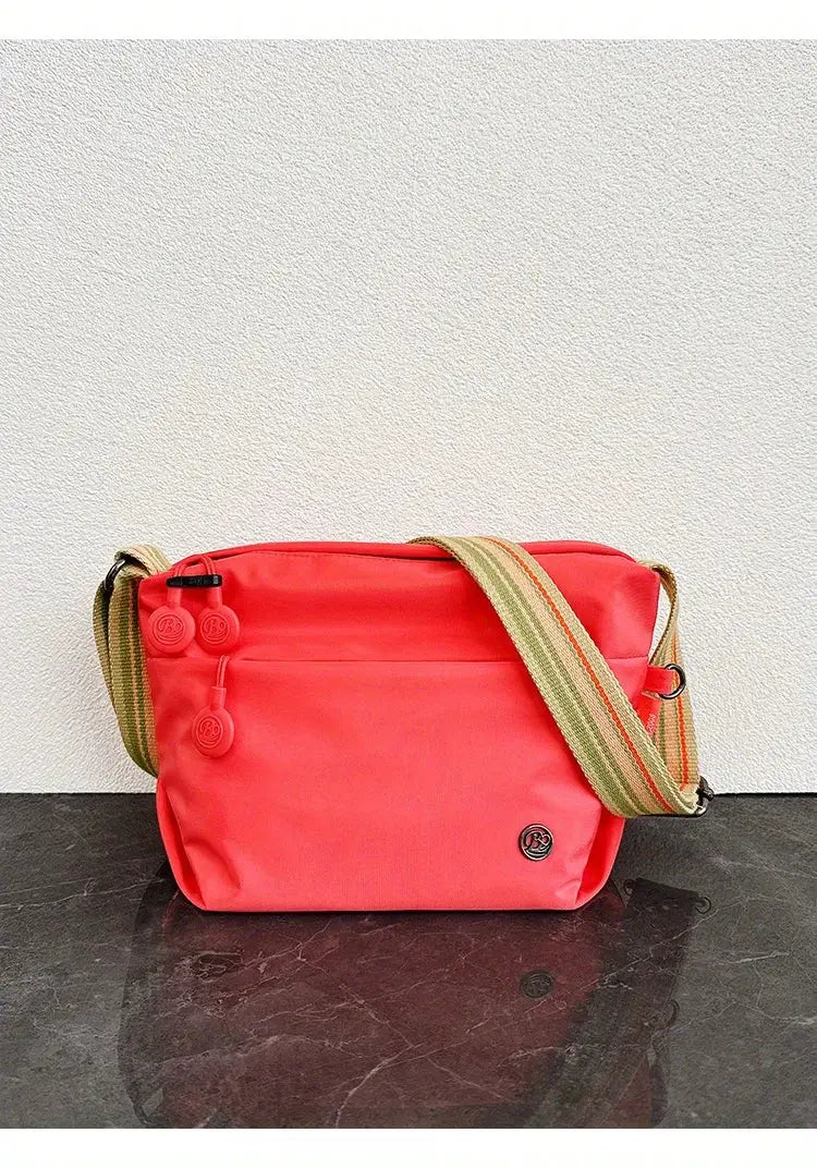 Simples Market coral nylon crossbody bag with adjustable striped strap and zipper closure