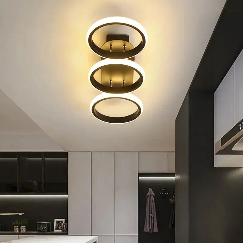 LED ceiling light three-ring fixture, modern black rings with gold/brass center, warm white glow