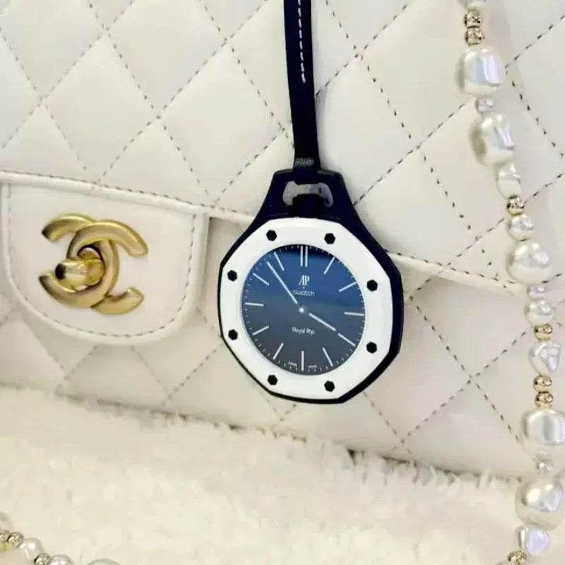 Swatch AP Royal Oak-style pendant watch with blue dial and white octagonal bezel on a white quilted Chanel bag