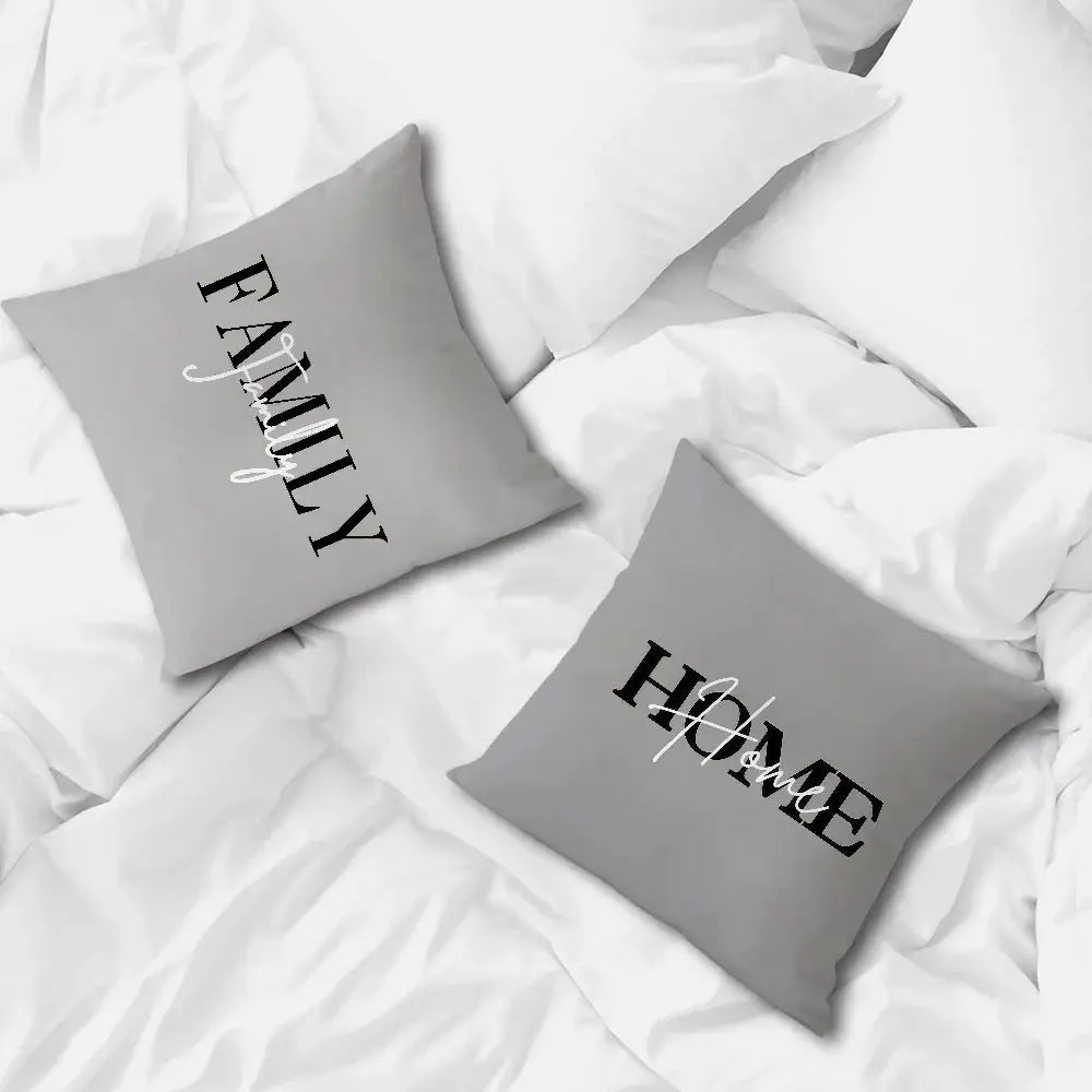 Gray pillowcases, two decorative cushions with bold black typography on white bedding.