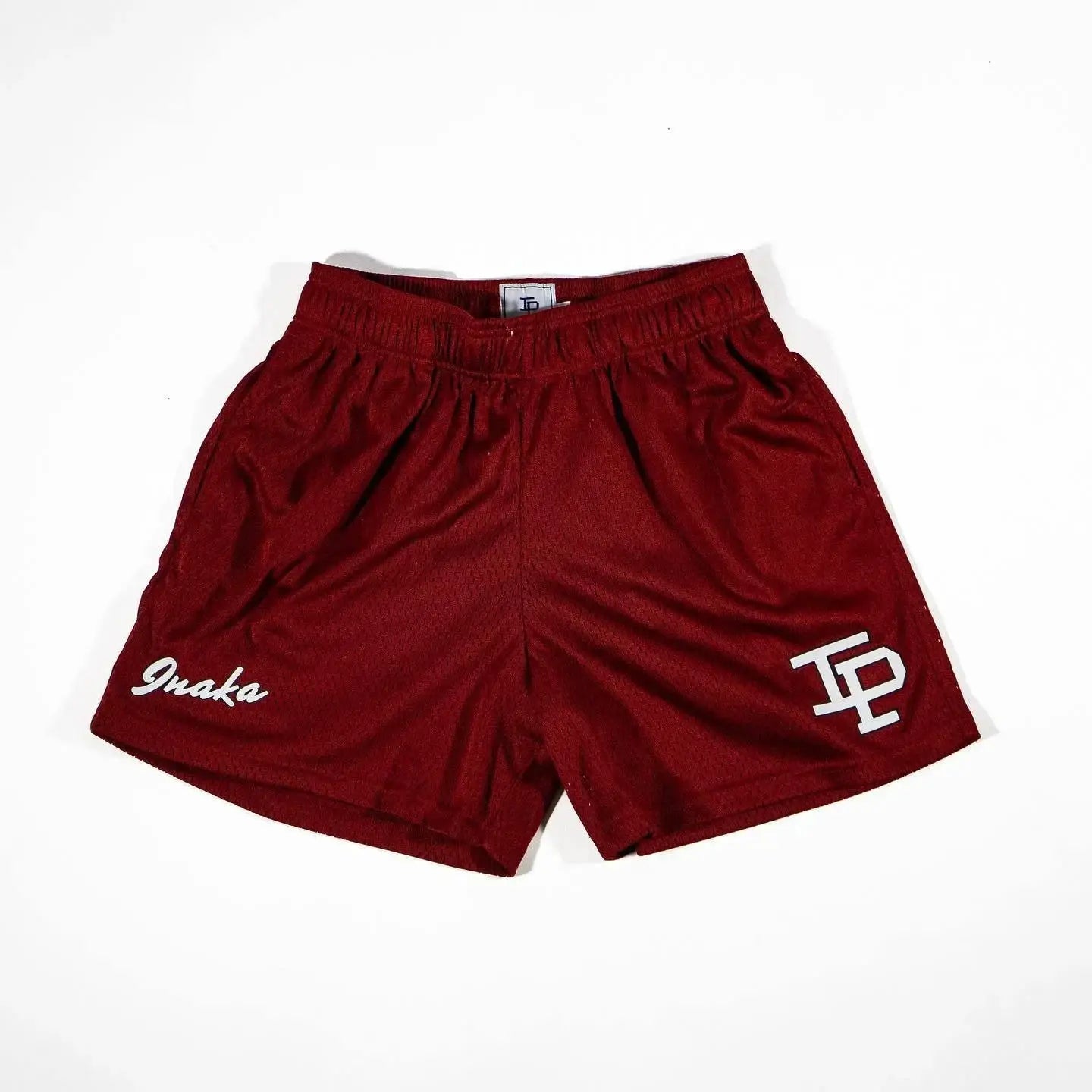 Mens red quick-dry mesh gym shorts with white Omaka logo on left leg and TP emblem on right.