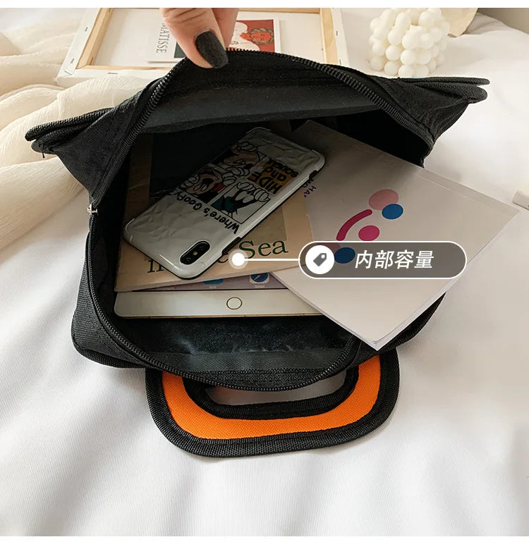 Simples Market black school backpack with orange interior, opened to reveal a phone and papers inside