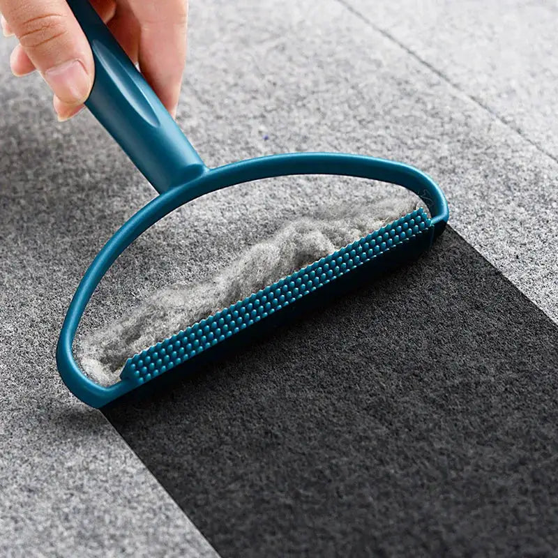Lint remover brush with blue handle and textured head for removing pet hair from carpet.