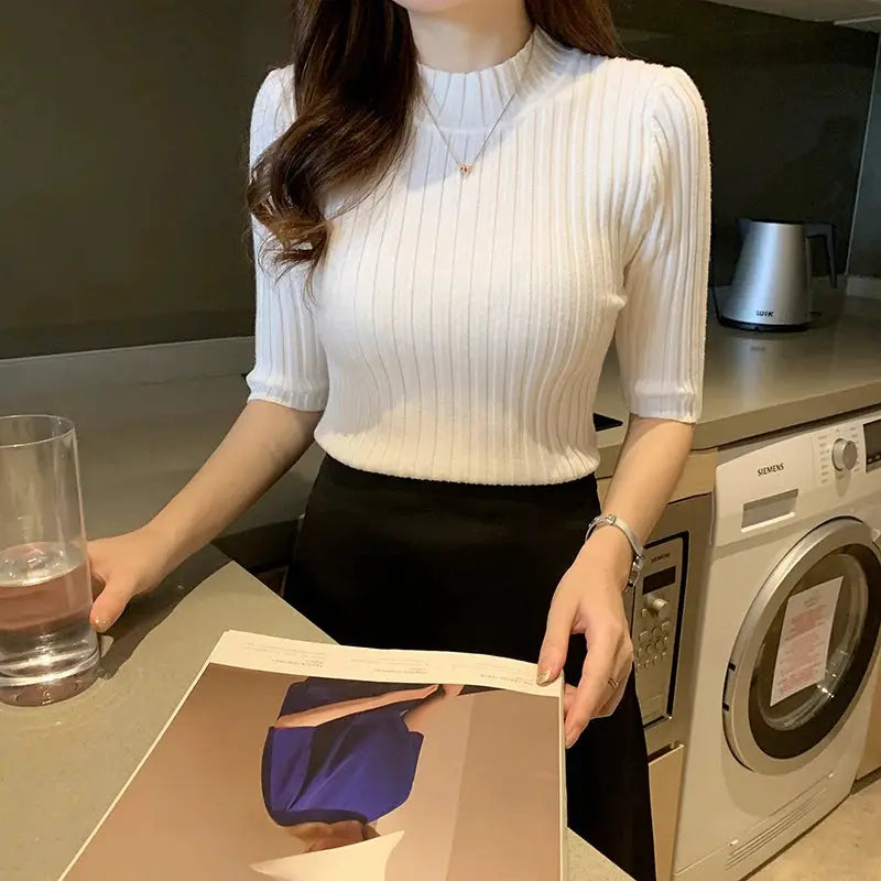 White ribbed knit short-sleeve blouse, form-fitting, worn by a woman