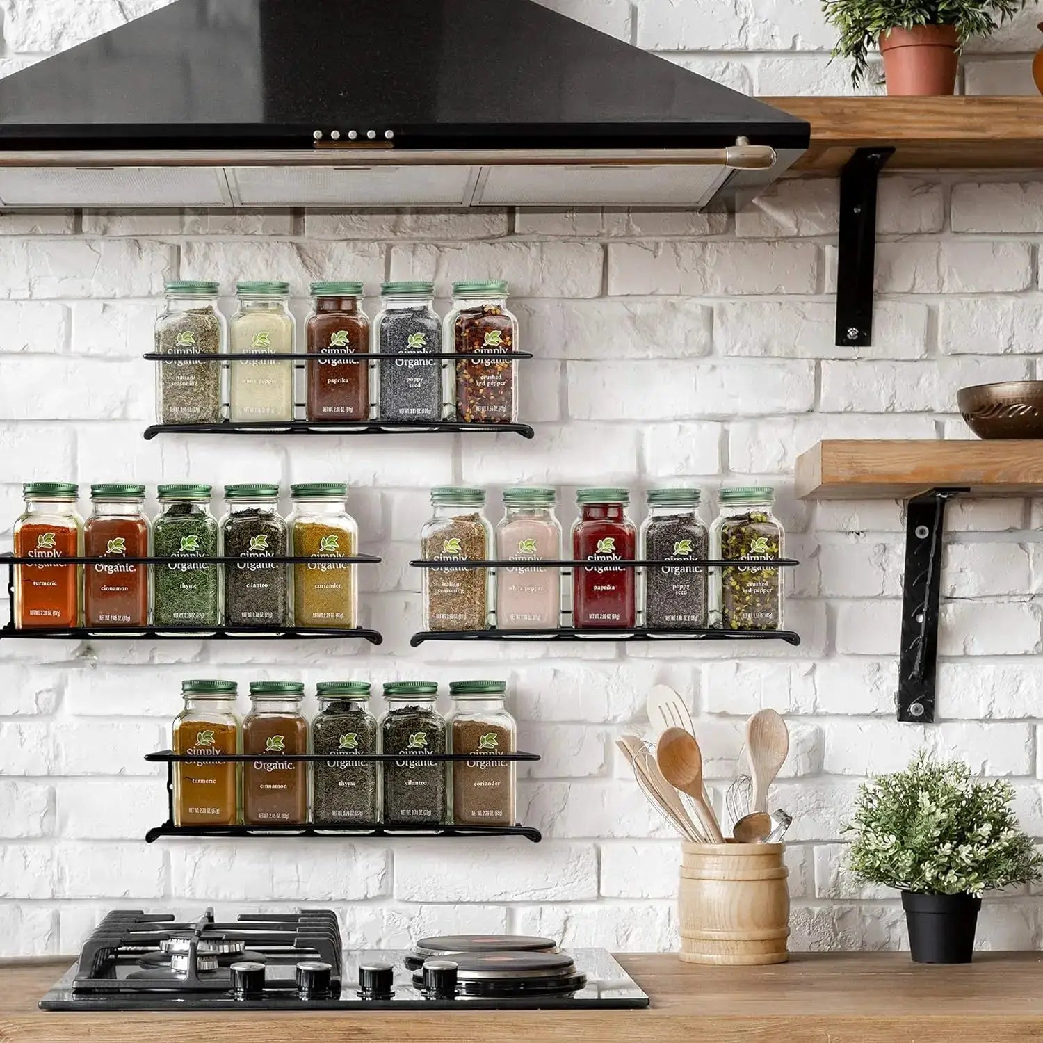 Simples Market iron wall-mounted spice rack with multiple glass jars and green caps on a white brick kitchen wall