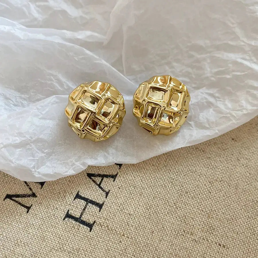 Two gold-tone irregular oval acrylic stud earrings with geometric square lattice design