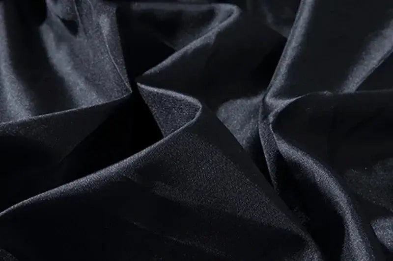 Jacket fabric close-up in black polyester with a smooth sheen and folds