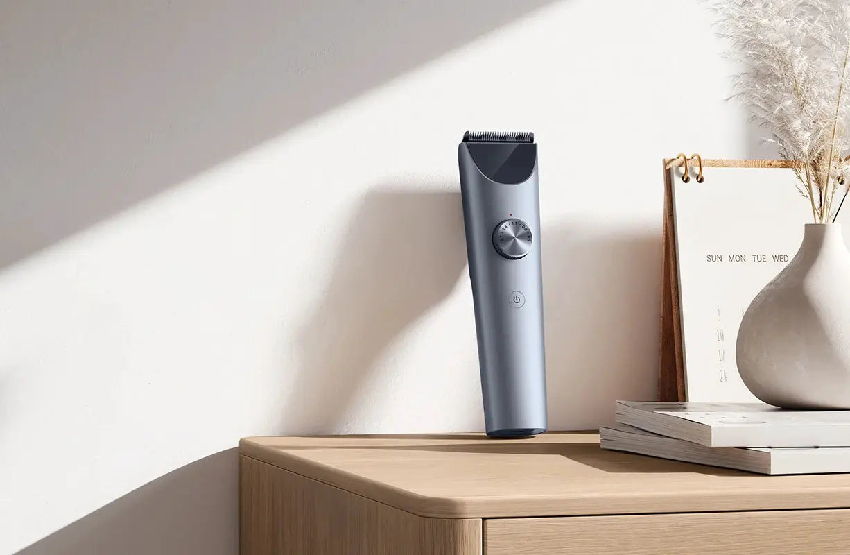 MIJIA Hair Clipper 2 cordless trimmer with titanium alloy blade, blue-gray finish on a wooden desk.