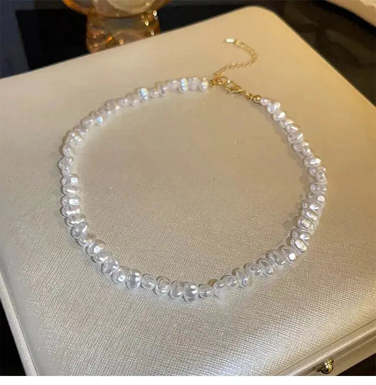 Imitation pearl necklace, white freshwater-pearls on a simple collarbone-length strand with a gold extender clasp.