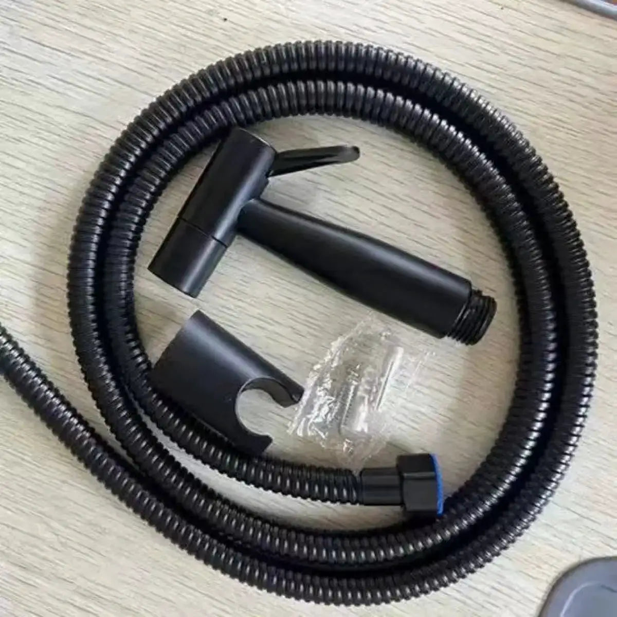Black handheld bidet sprayer set with coiled hose and wall-mount bracket for toilet.