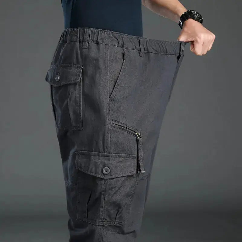 Men's dark gray tactical cargo pants with elastic waist and multiple pockets, including a zippered side pocket.