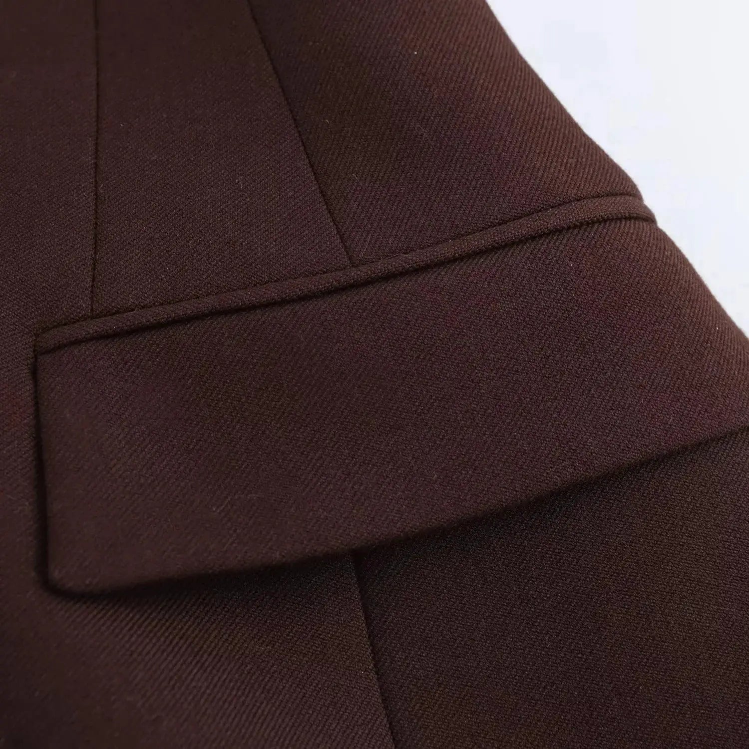 KONDALA blazer close-up: brown textured fabric with welt pocket detail.