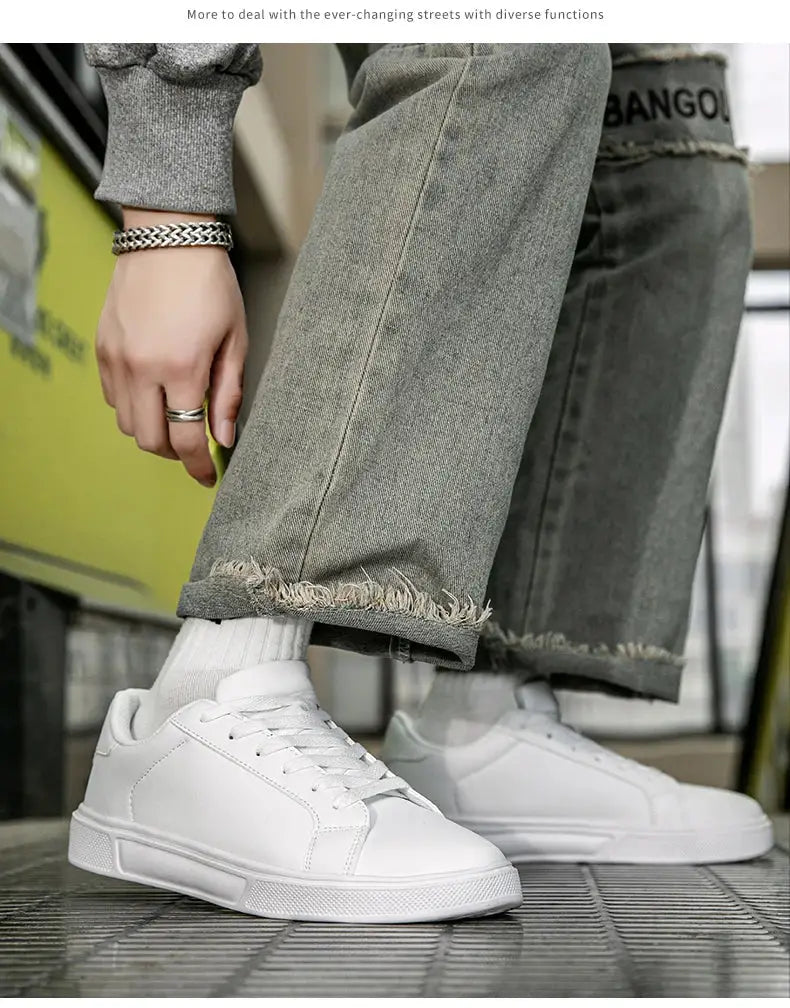 Pair of white PU leather men's sneakers, casual vulcanized style shown with cuffed gray jeans.