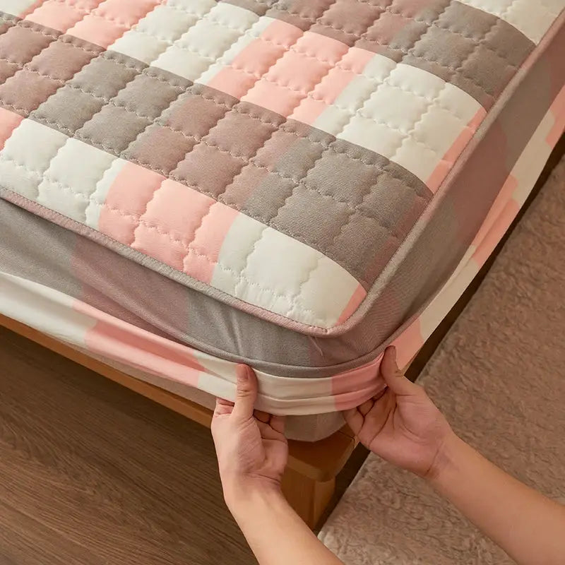 Simples Market quilted plaid mattress protector in pink, gray, and white.