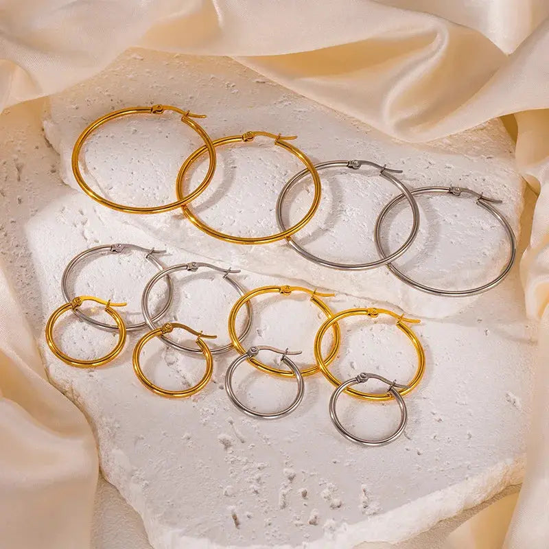 Unisex hoop earrings set in gold-tone and silver stainless steel with large and small circle hoops.