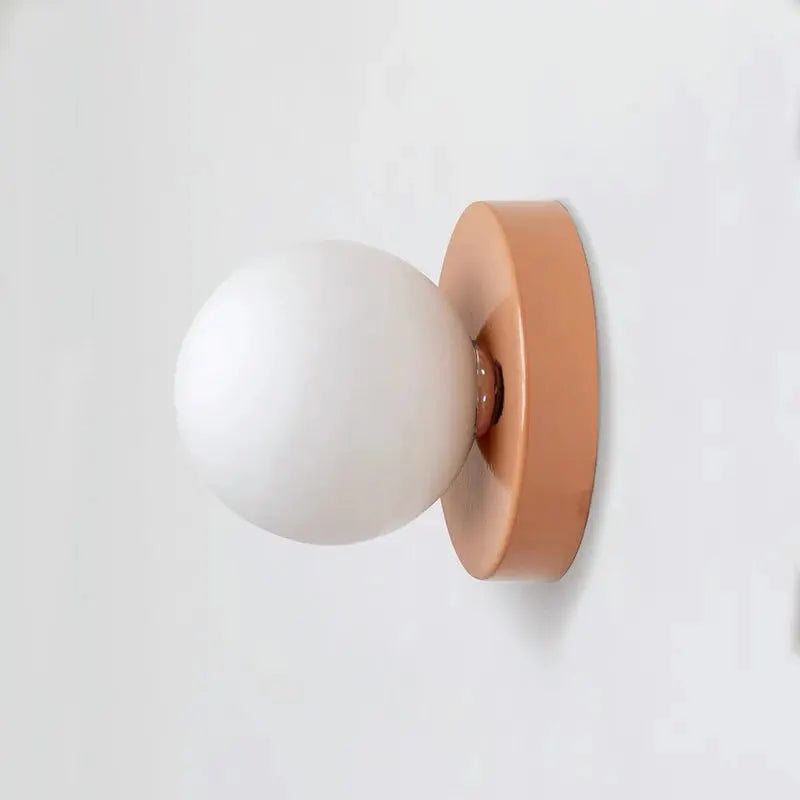 Macaron wall lamp by Simples Market with white plastic globe shade and peach iron backplate