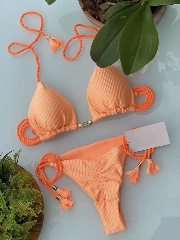 Peach ribbed bikini set with rope-tie straps and tassel ends; backless triangle top and side-tie bottoms.