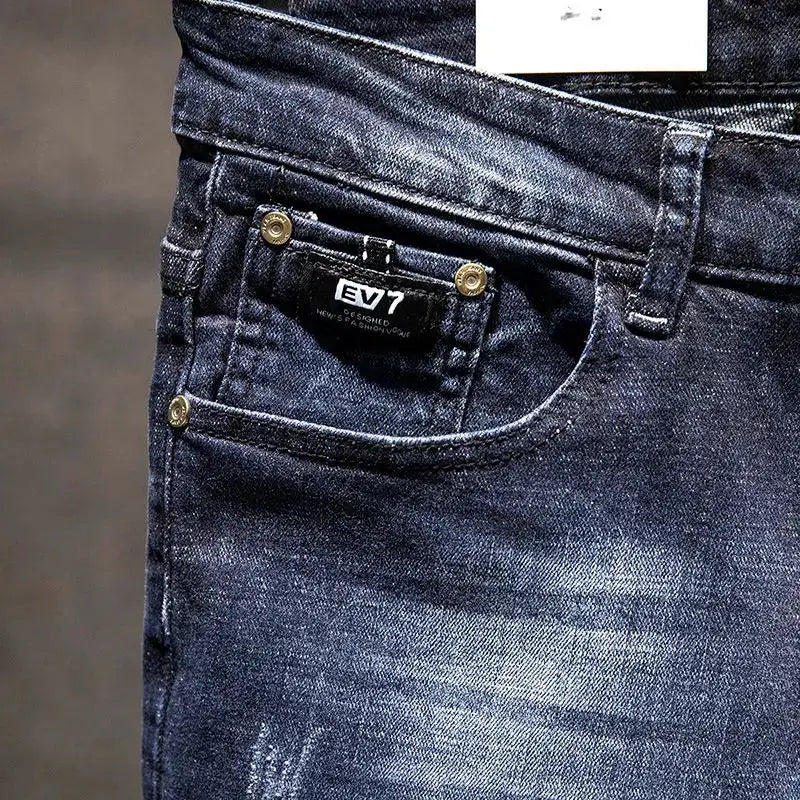 Men's dark blue denim jeans with distressed wear, EV7 patch on front pocket