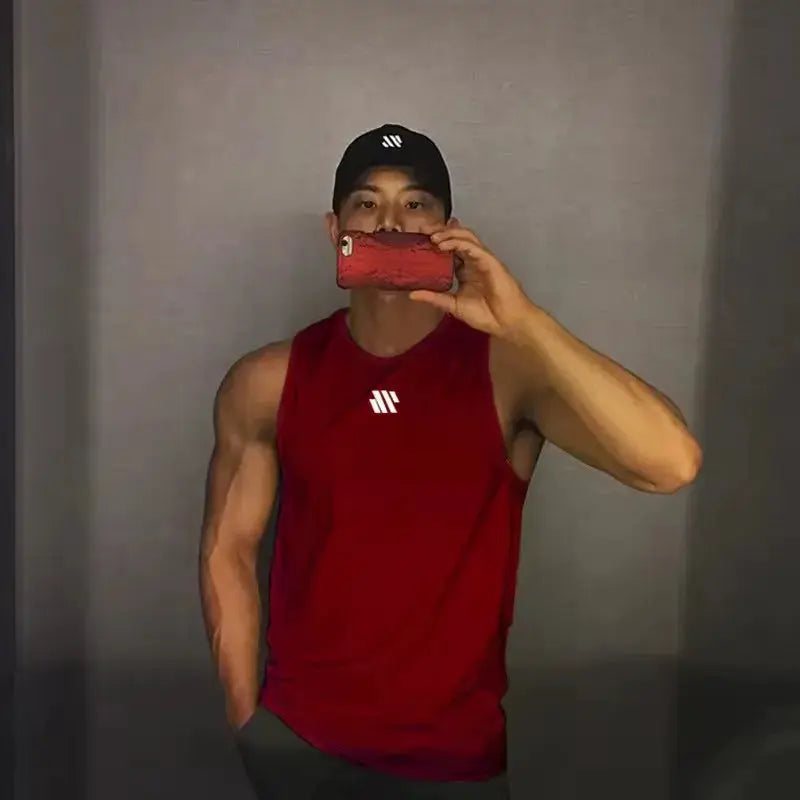 Simples Market men's red sleeveless gym tank top with white chest logo worn by a muscular man taking a mirror selfie.