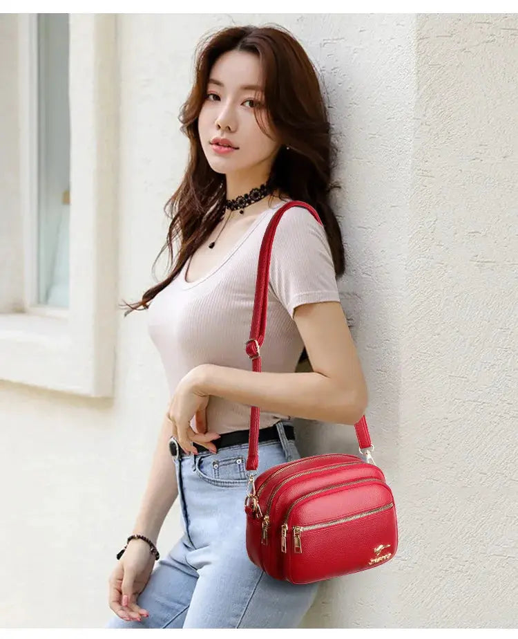 Red leather crossbody bag with two front zip pockets and an adjustable strap