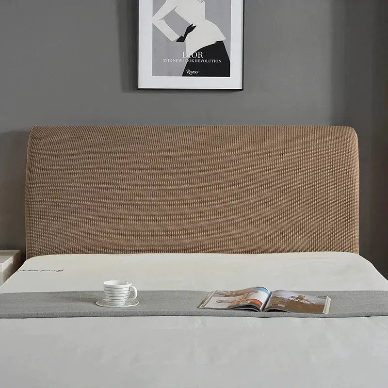 Bed headboard cover in brown textured fabric with a gray bed runner and a magazine on a neatly made bed