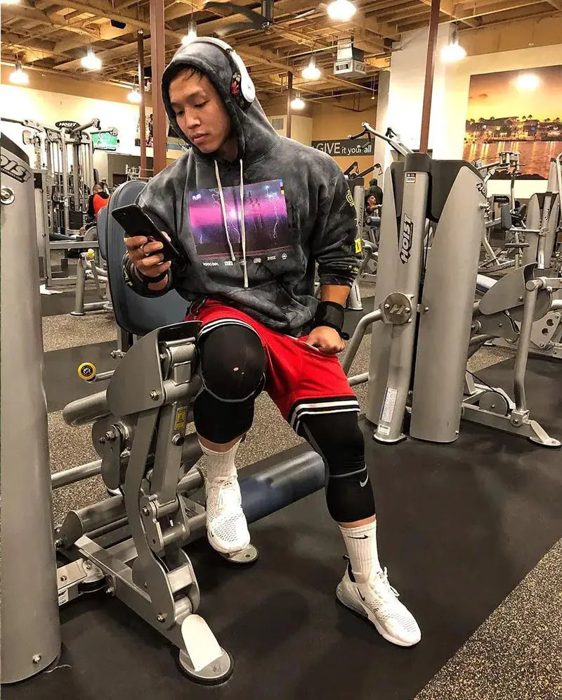 Men's basketball shorts in red mesh quick-dry fabric, worn with black leggings at the gym