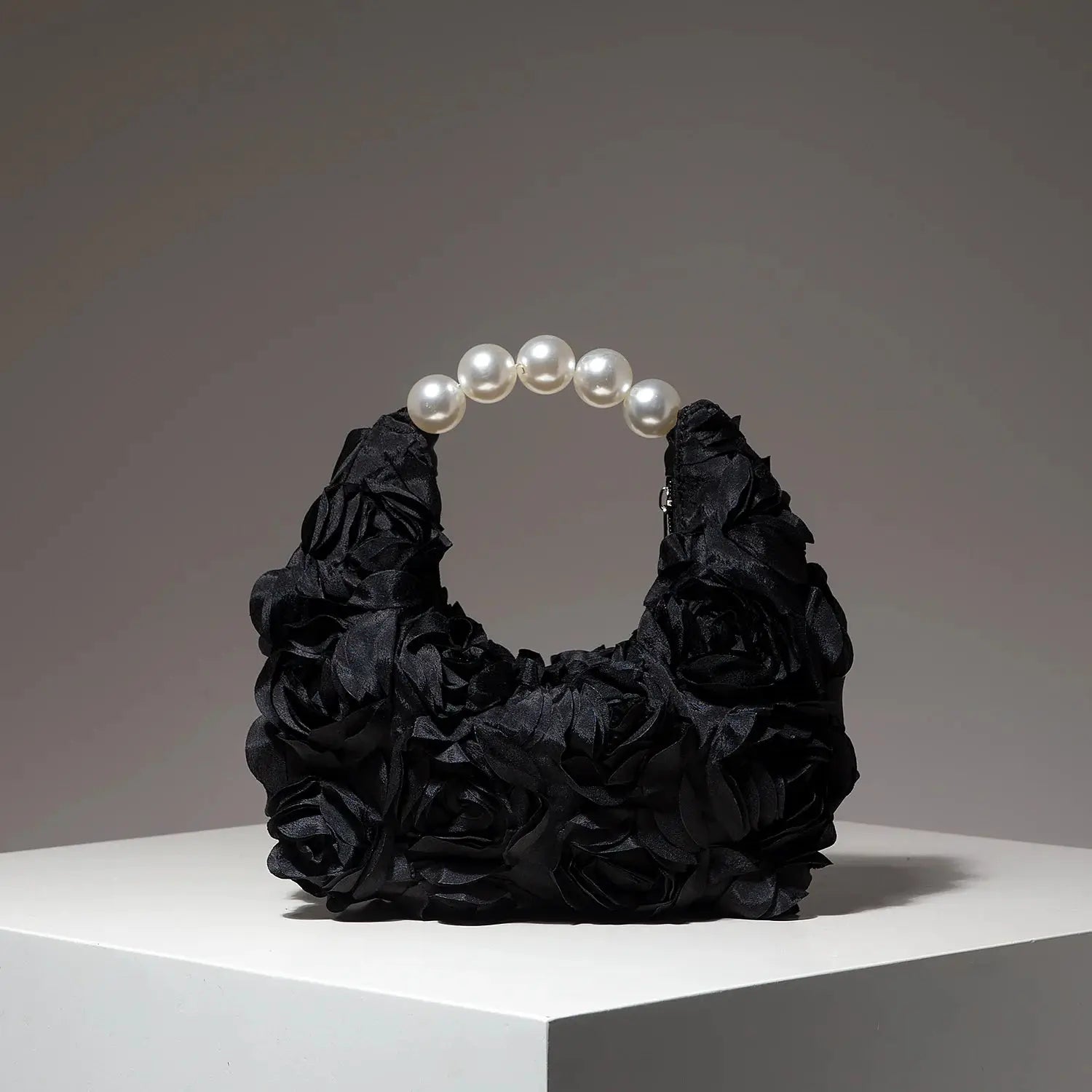 Clutch bag with black floral rosette design and a pearl bead handle