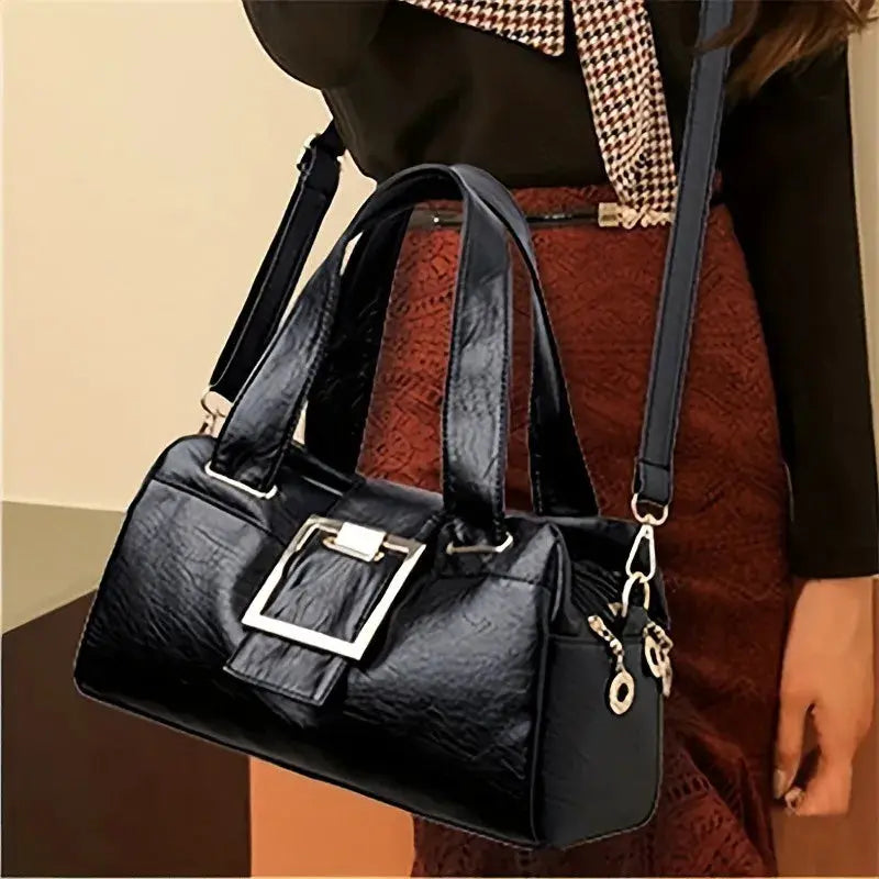 Women's black leather multi-layer top-handle handbag with a prominent gold square buckle and attached shoulder strap.