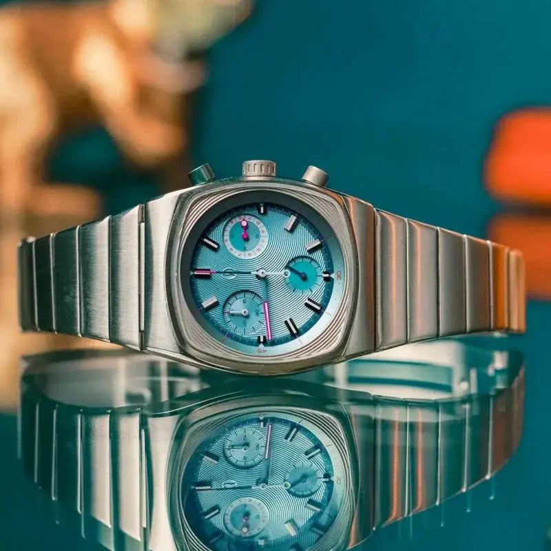CILOA stainless steel men's watch with turquoise dial, chronograph subdials, and brushed bracelet.