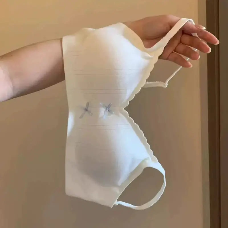 White backless sports bra with gathered sides and blue X-stitch accents, breathable stretchy fabric