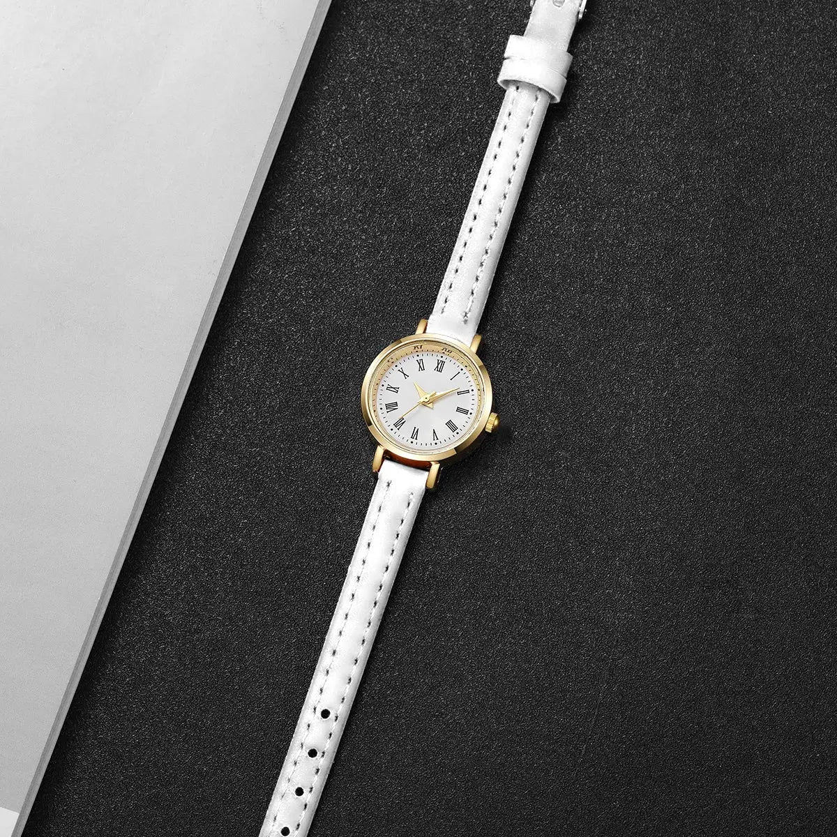 Women’s watch with white leather strap, gold-tone case and Roman numeral dial.